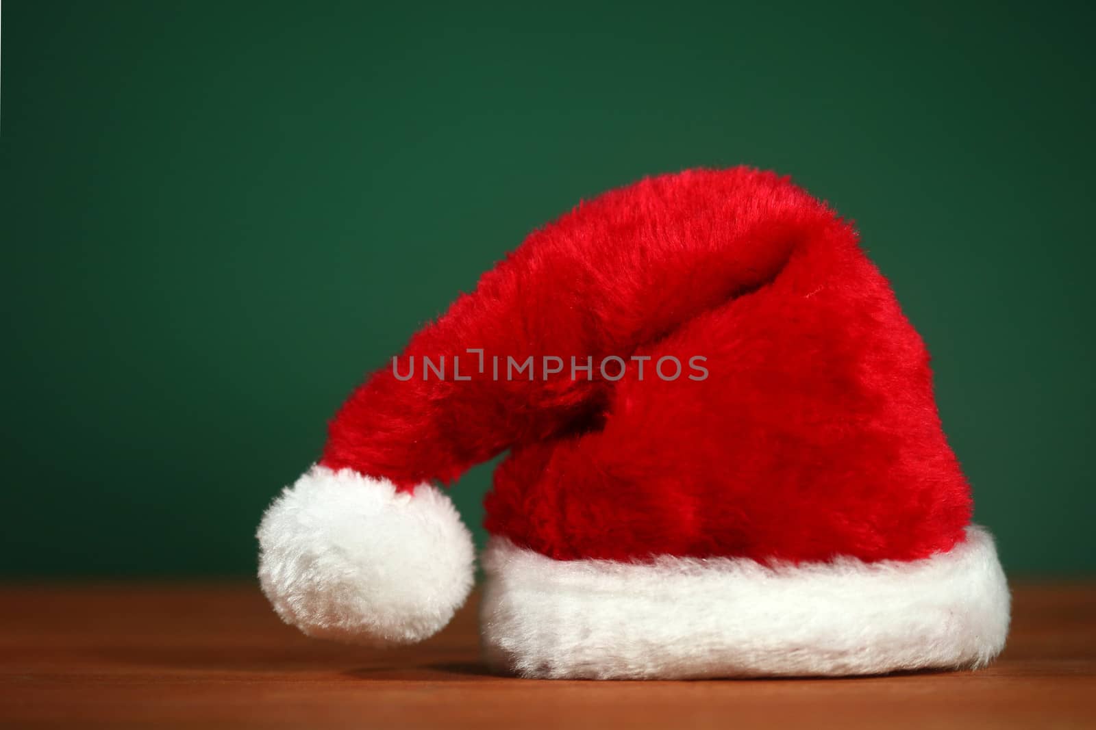 Santa Clause Red Hat With Copy Space on Green and Wood Background