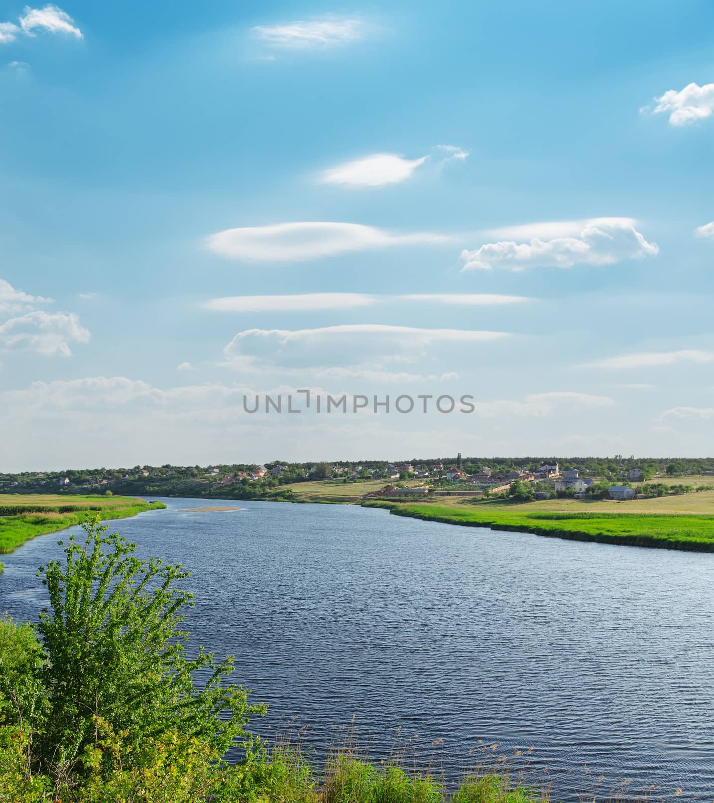 river with green riverside and light cloudy sky by mycola