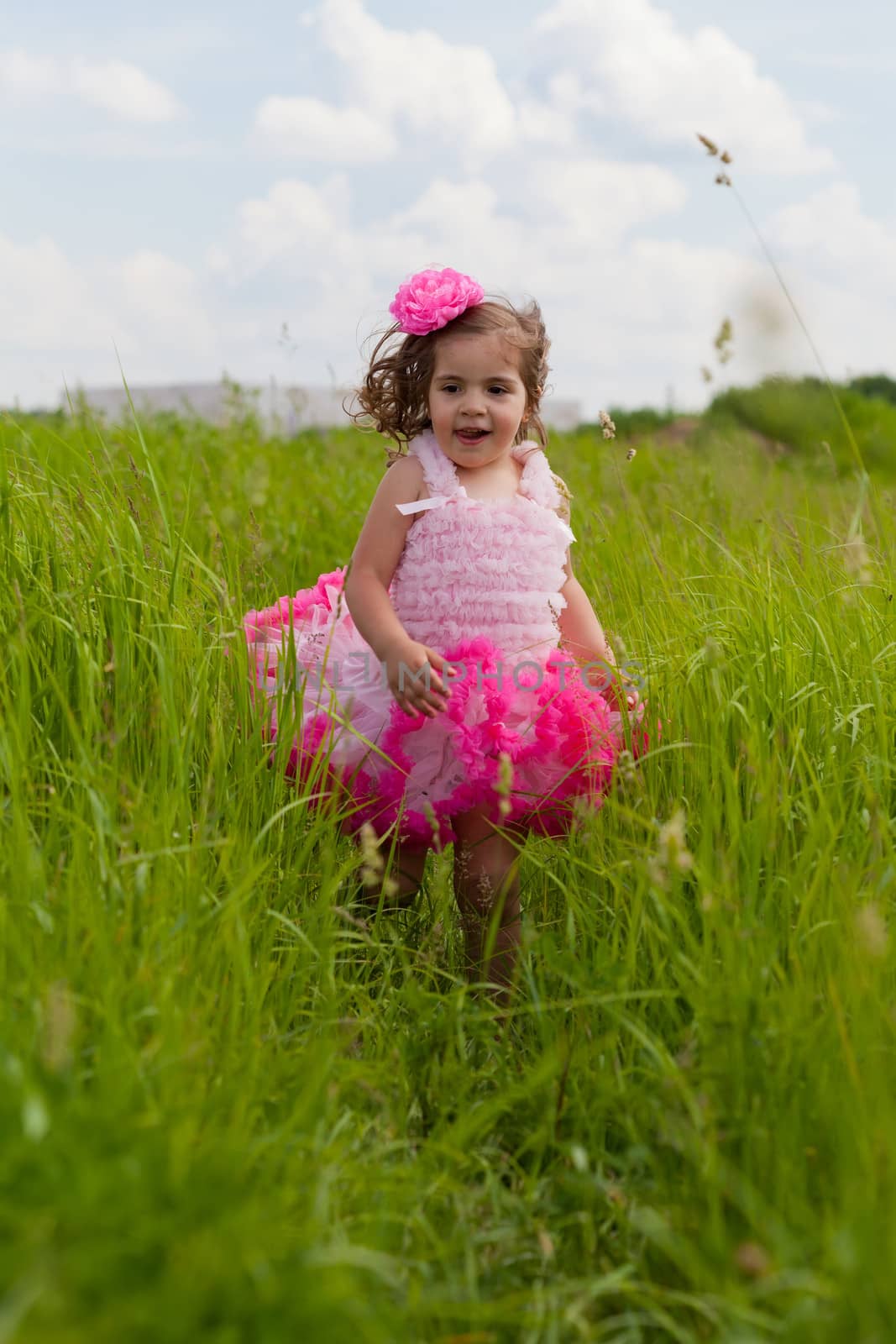 little girl in a pink dress runs on a grass