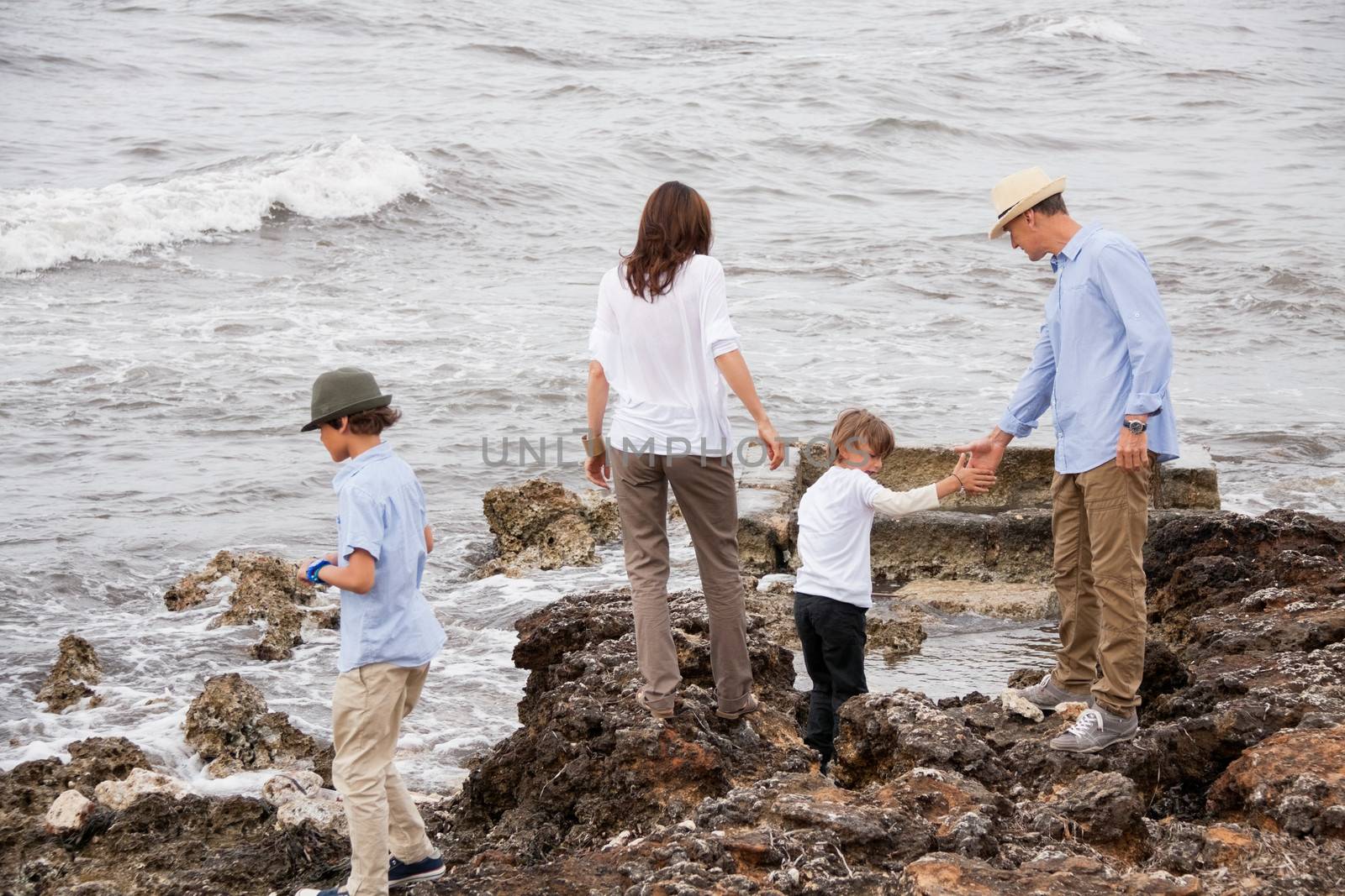 happy family sitting on rock and watching the ocean waves holiday 