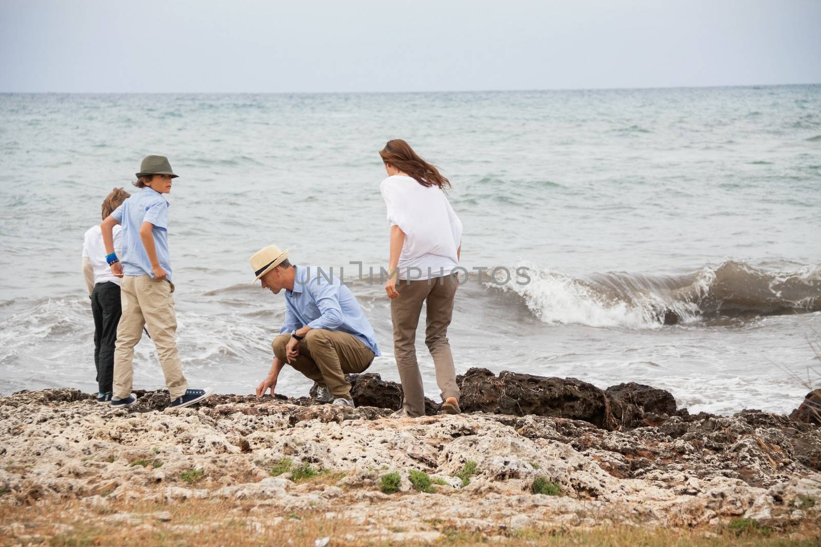 happy family sitting on rock and watching the ocean waves holiday 