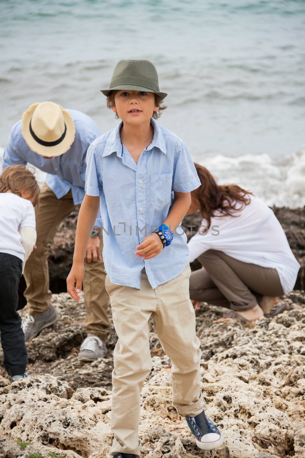 happy family sitting on rock and watching the ocean waves by juniart