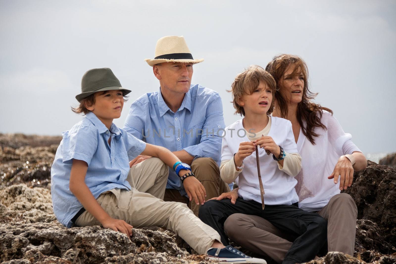 happy family sitting on rock and watching the ocean waves holiday 