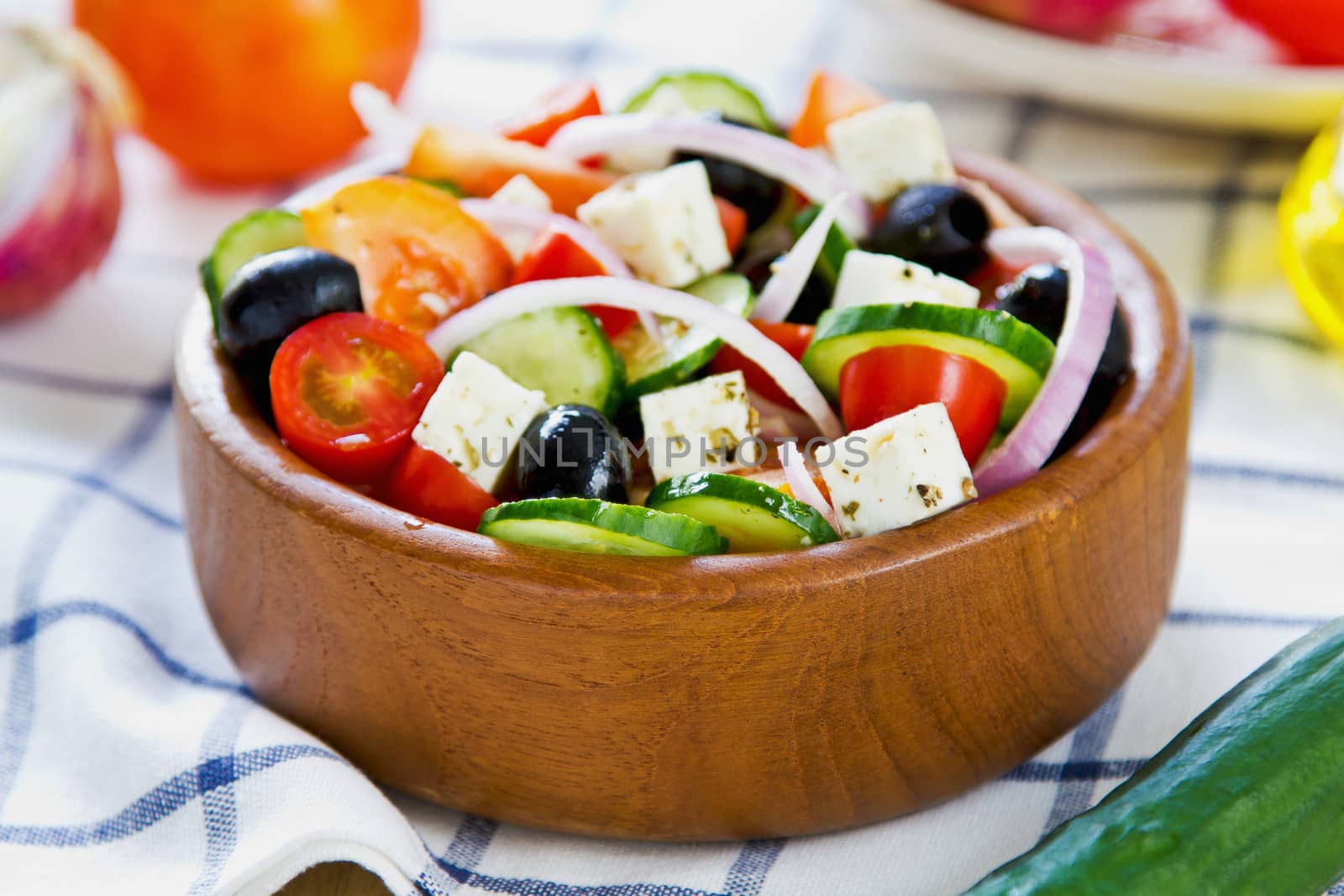 Greek salad in a wood bowl by fresh ingredients