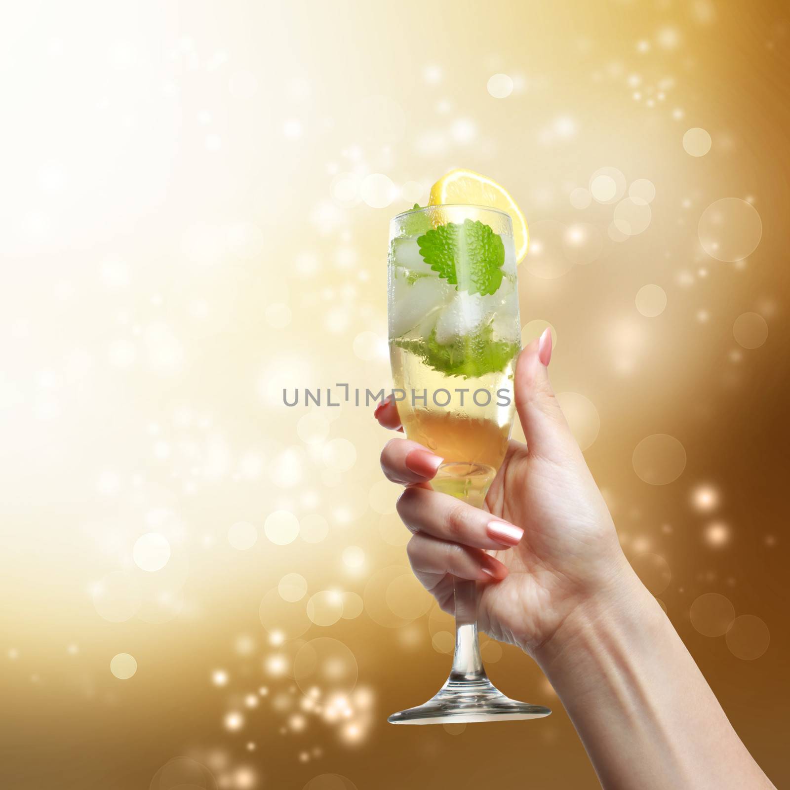 Champagne glass being lifted up in the air by a young woman on golden shinning background