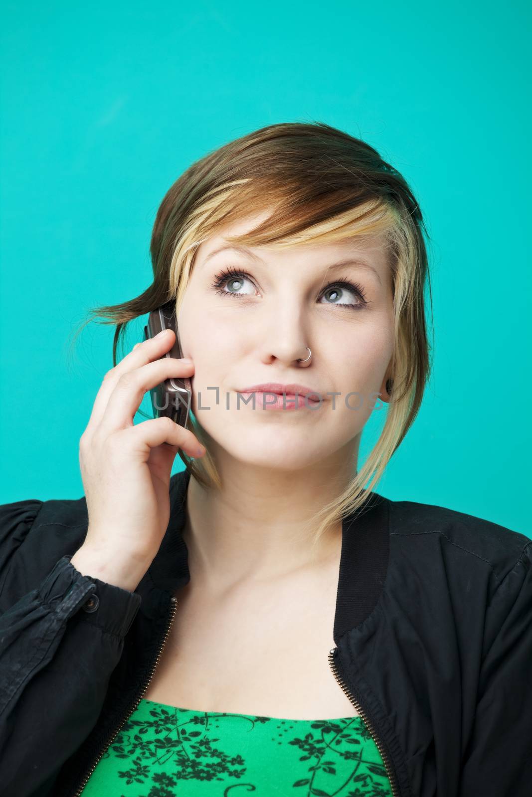 young woman chatting on a cell phone over a green wall