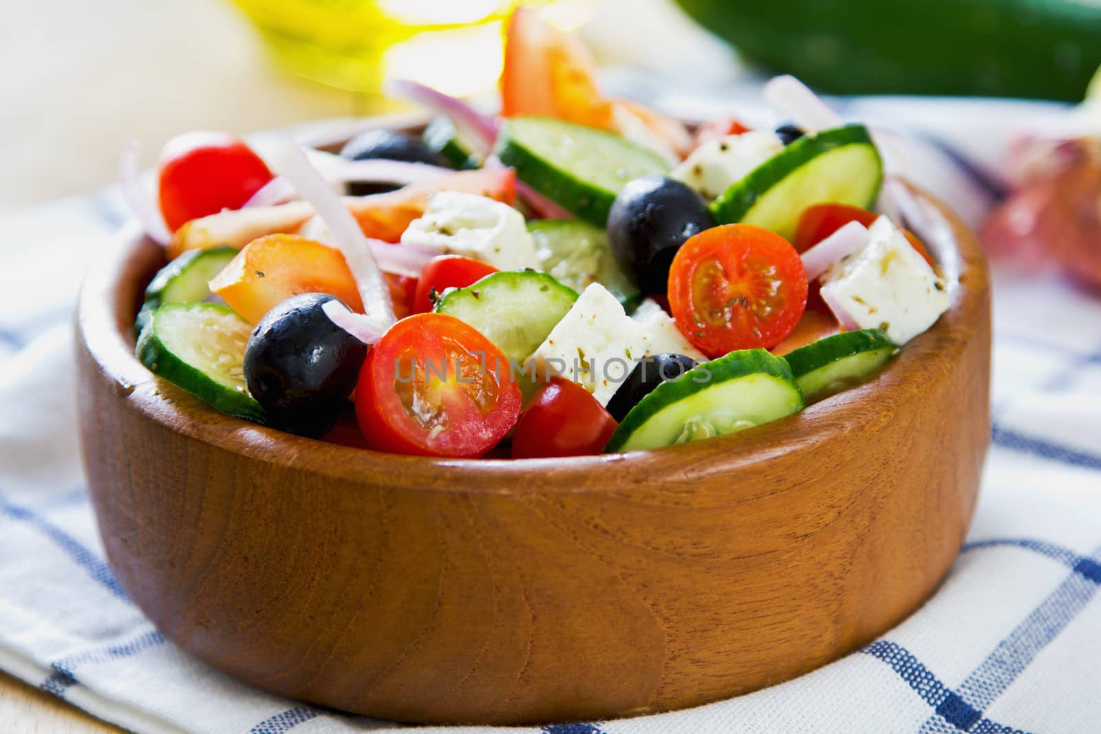 Greek salad in a wood bowl by fresh ingredients