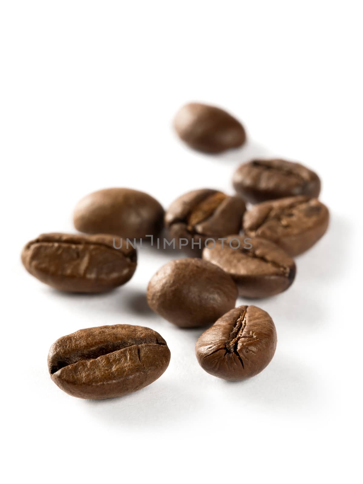 Macro photo of a small bunch of roasted coffee beans. Focus is on the first bean.
