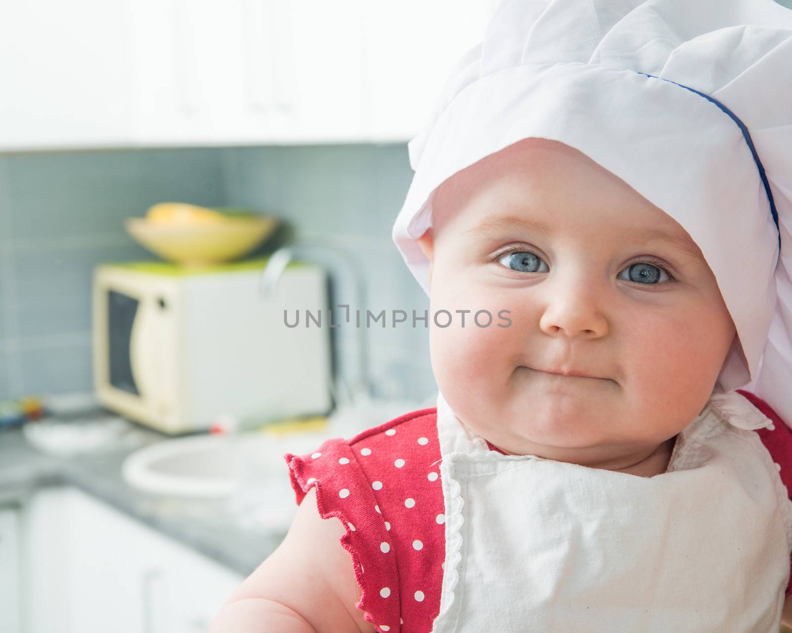 little cute baby with a chef's hat in the kitchen