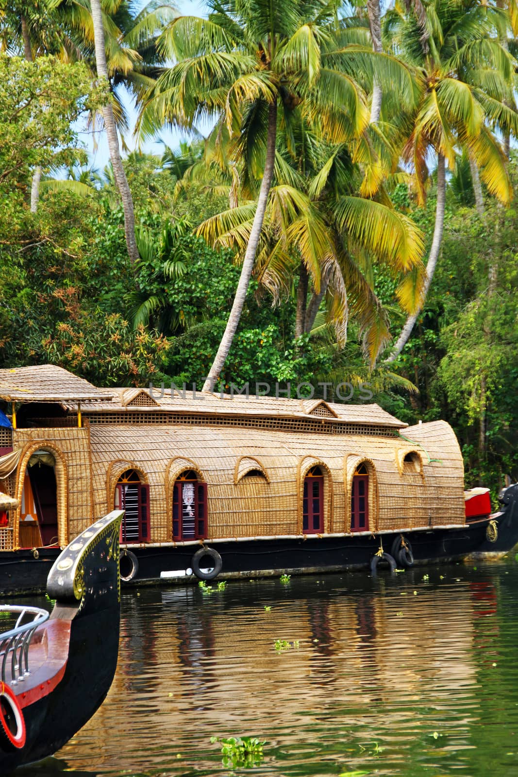 A rice barge turned into tourist house boat slowly cruising in the waters of the Venbanadu lake of Kerala, India