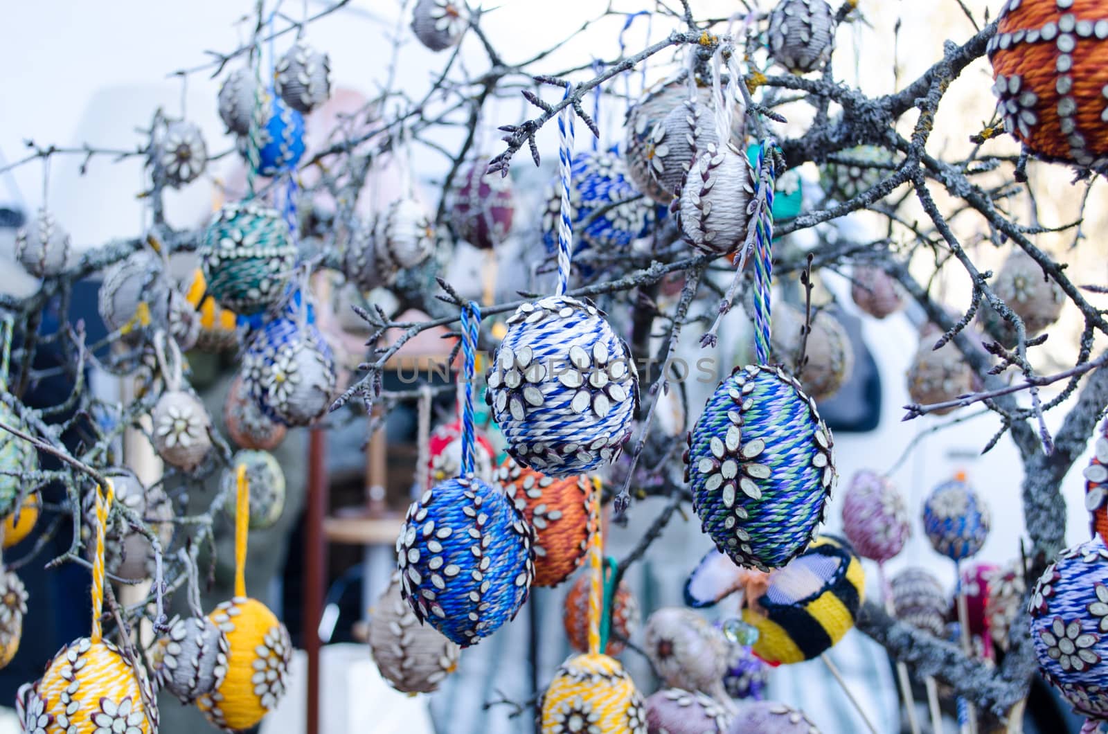 handmade easter eggs imitation decorations hang on tree branches sold in outdoor spring market fair.