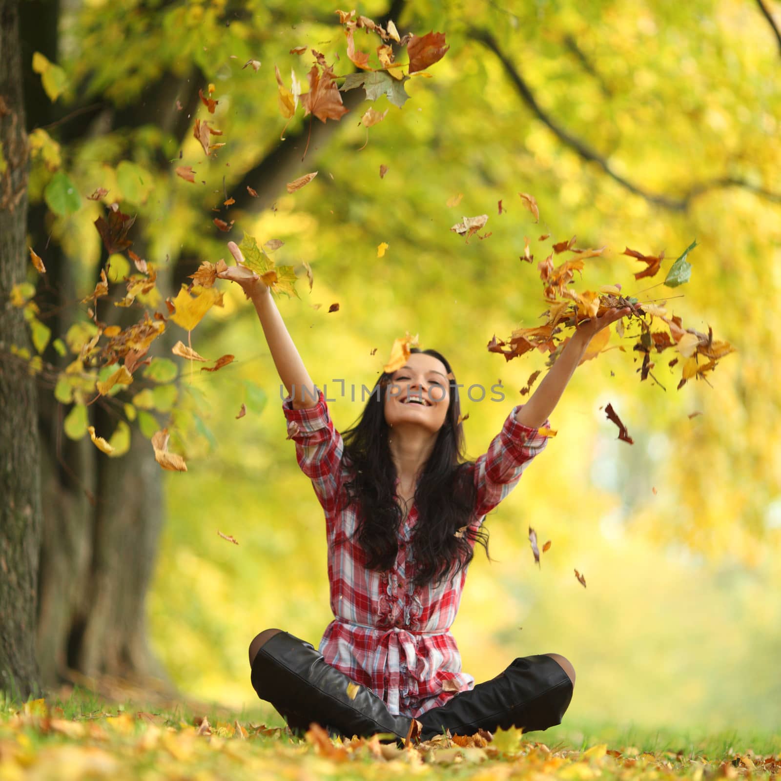 woman drop up leaves in autumn park