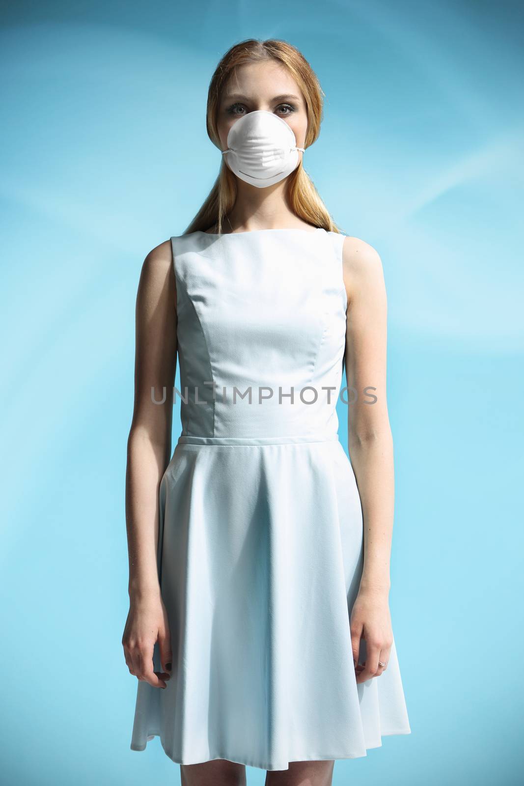 Beautiful girl in a white dress with a respiratory mask on her face
