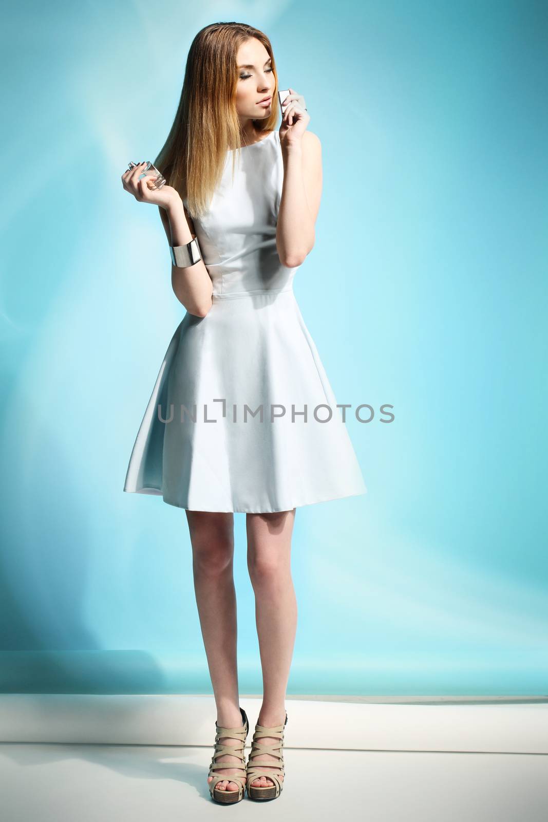 Beautiful girl in a white dress smelling perfume by robert_przybysz