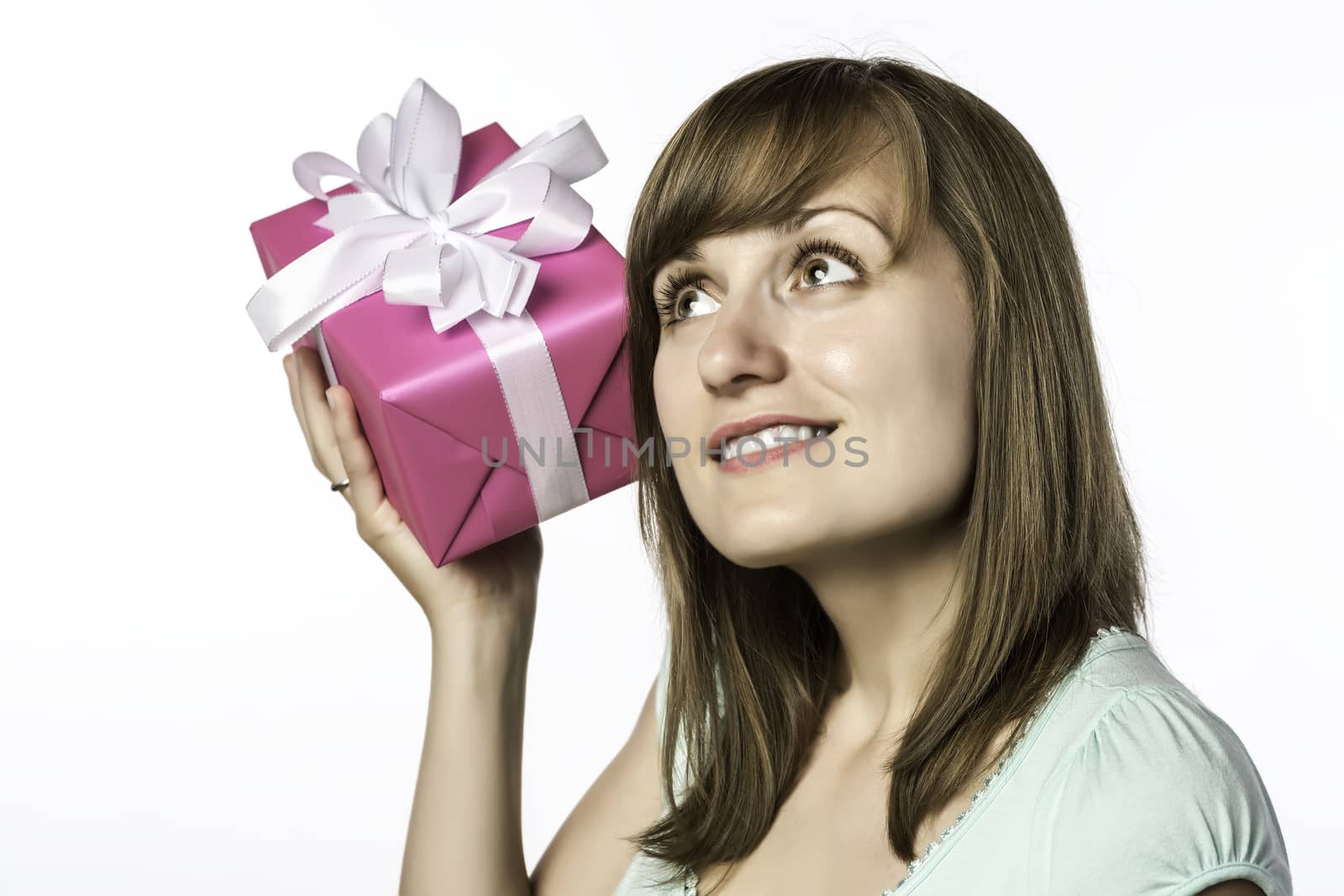 Young beautiful girl listens to a gift, isolated on white background