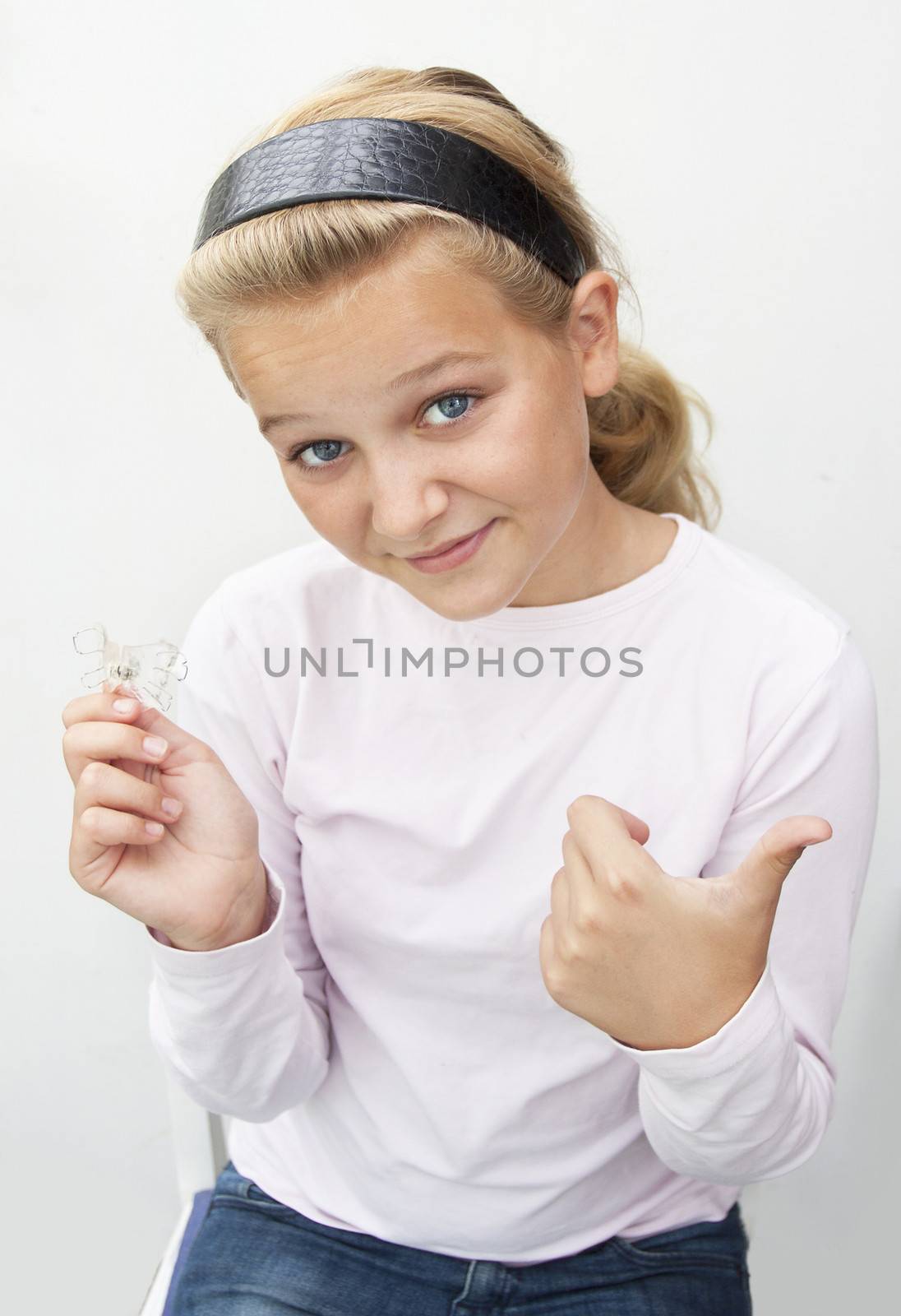 A girl holding up braces doing a thumbs up