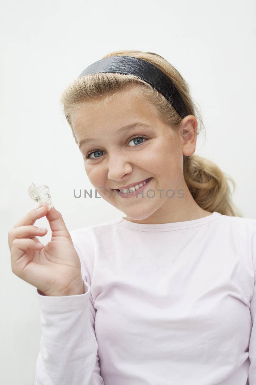 A young girl holding up braces looking at camera