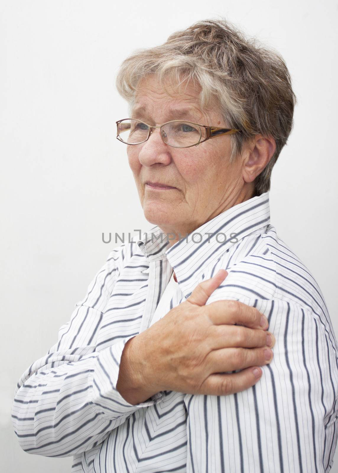A retired pensioner lady rubbing her painful shoulder