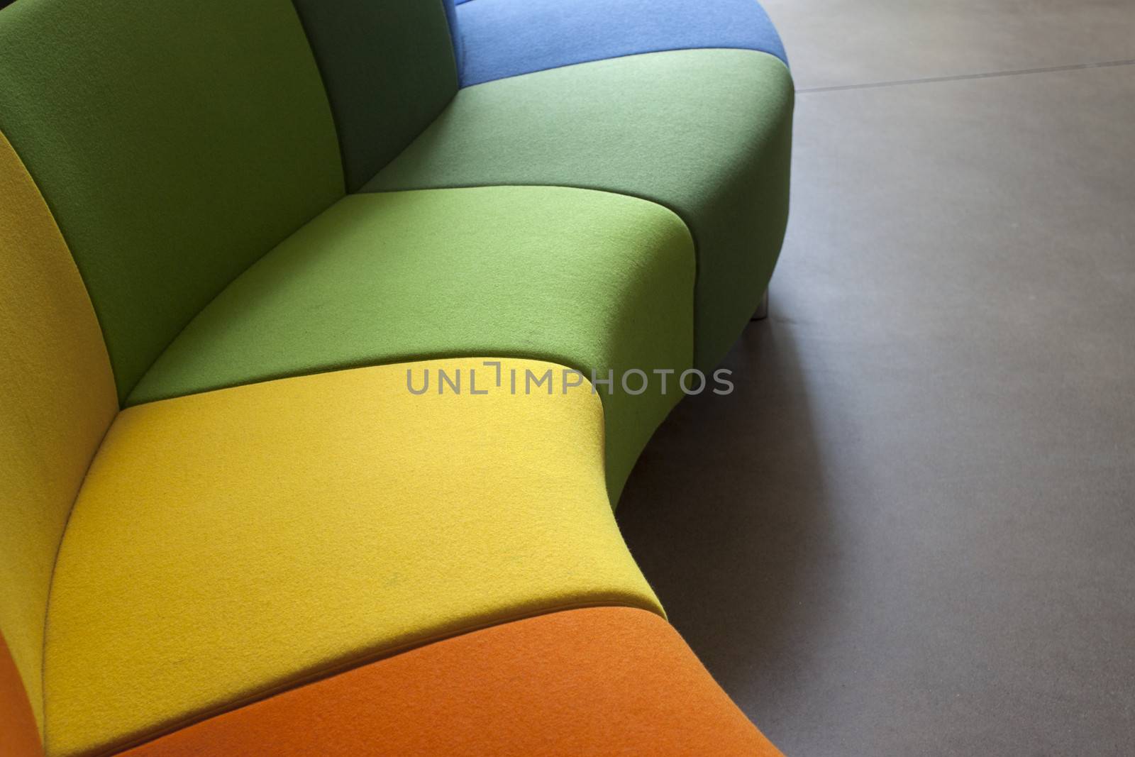 Detail of a curved sofa in green, orange and yellow
