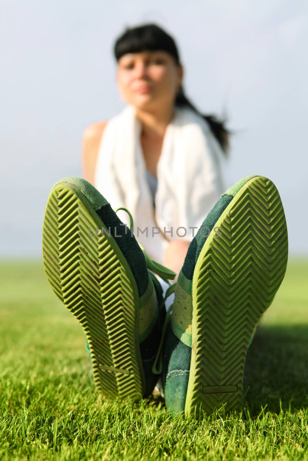 green sole of shoes on grass, tired sportswoman