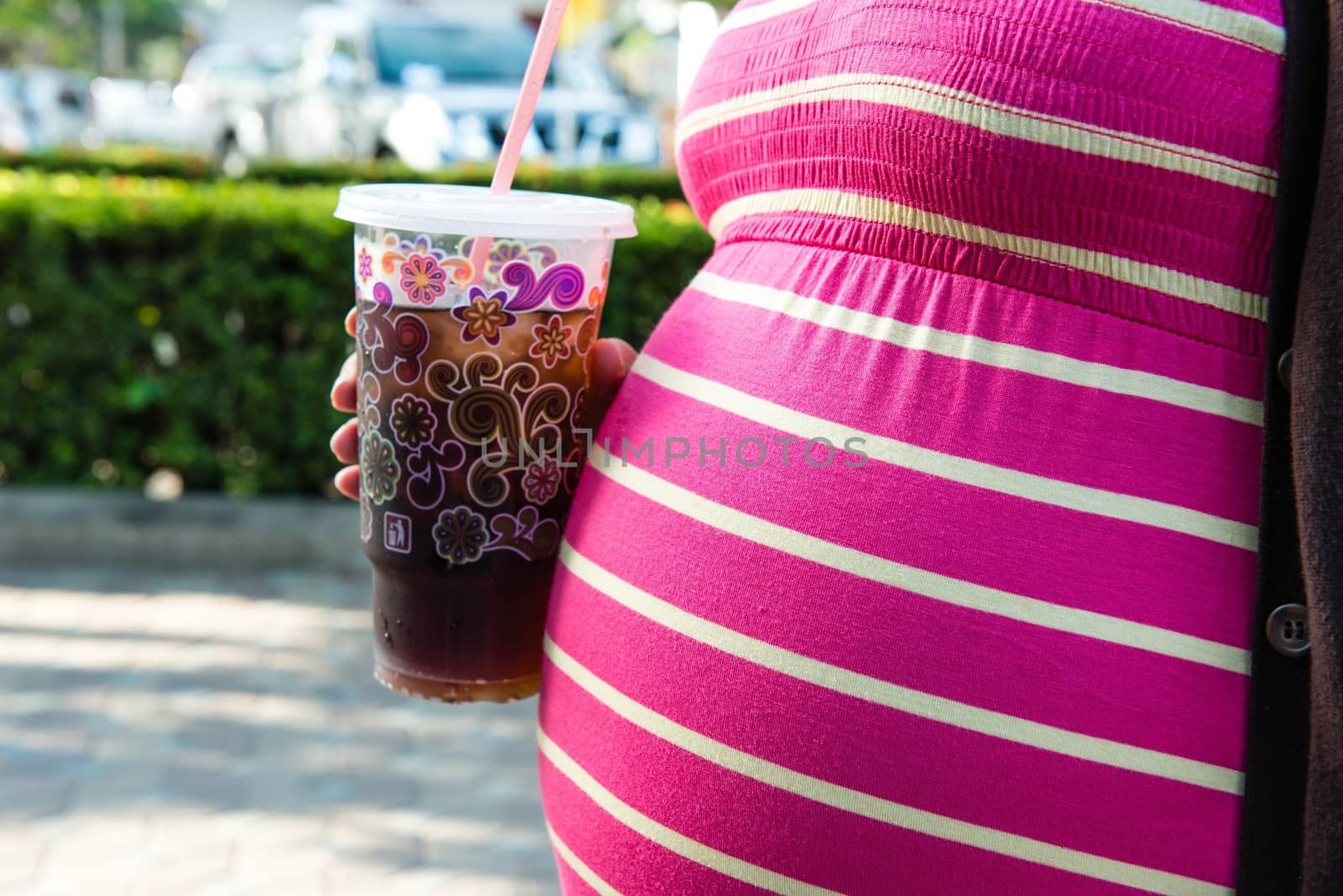 Asian pregnant woman holding a cup of softdrink by sasilsolutions