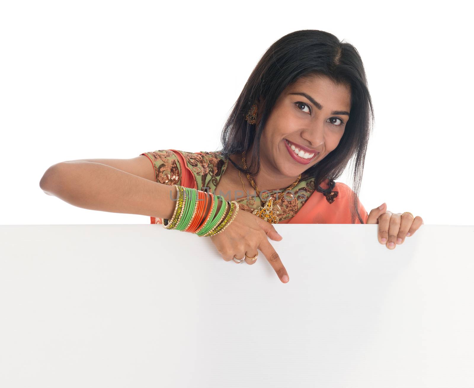 Traditional Indian woman in sari holding and pointing to blank billboard. Portrait of attractive young Asian female model isolated on white background.