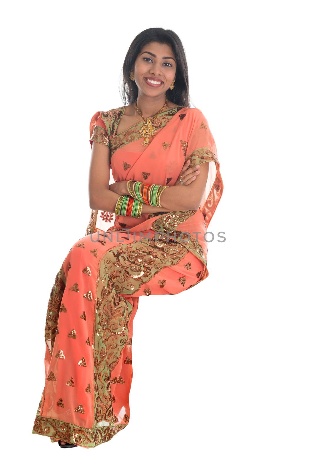 Full body traditional Indian woman in sari sitting on a transparent chair isolated over white background.