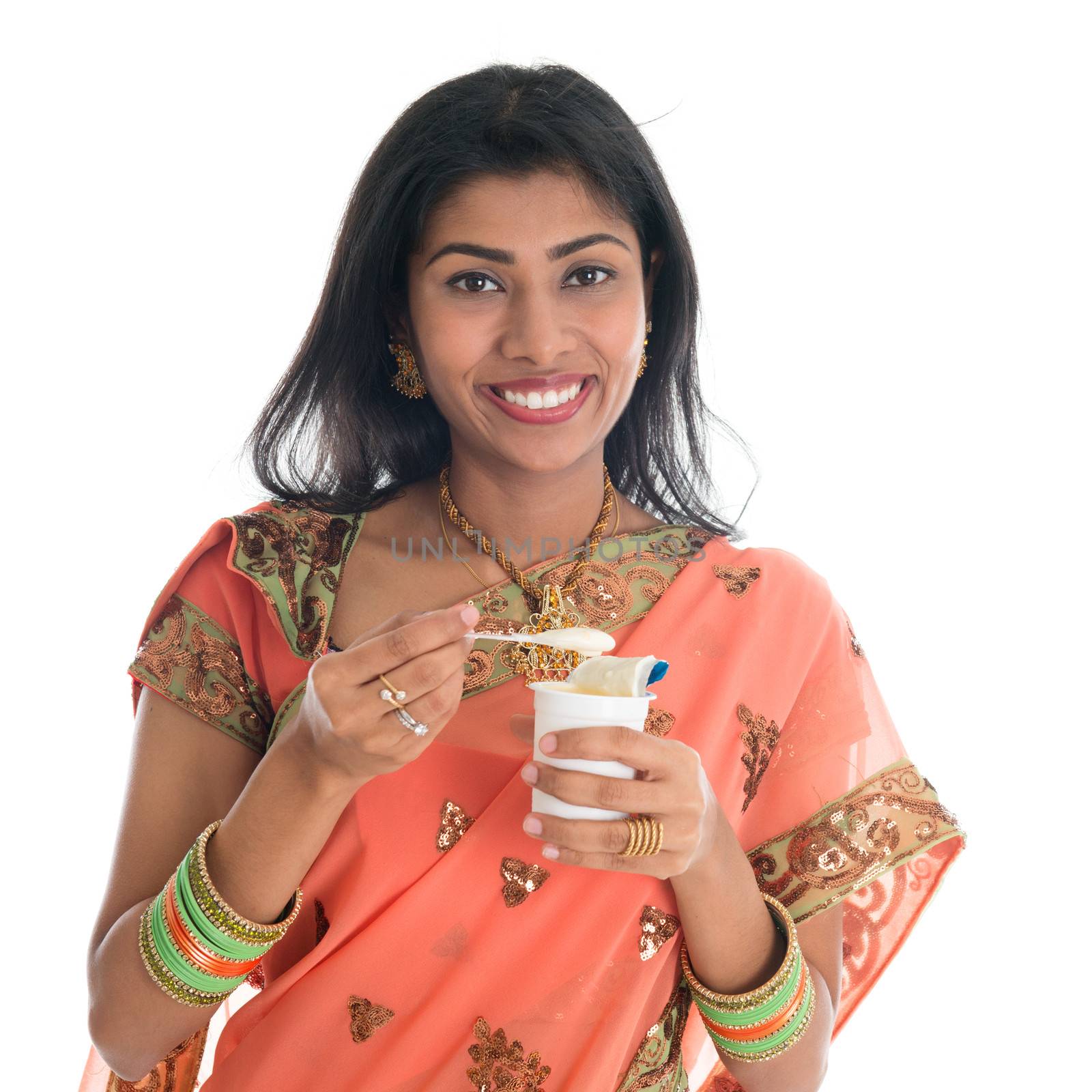 Happy Traditional Indian woman in sari eating yogurt, isolated on white background.