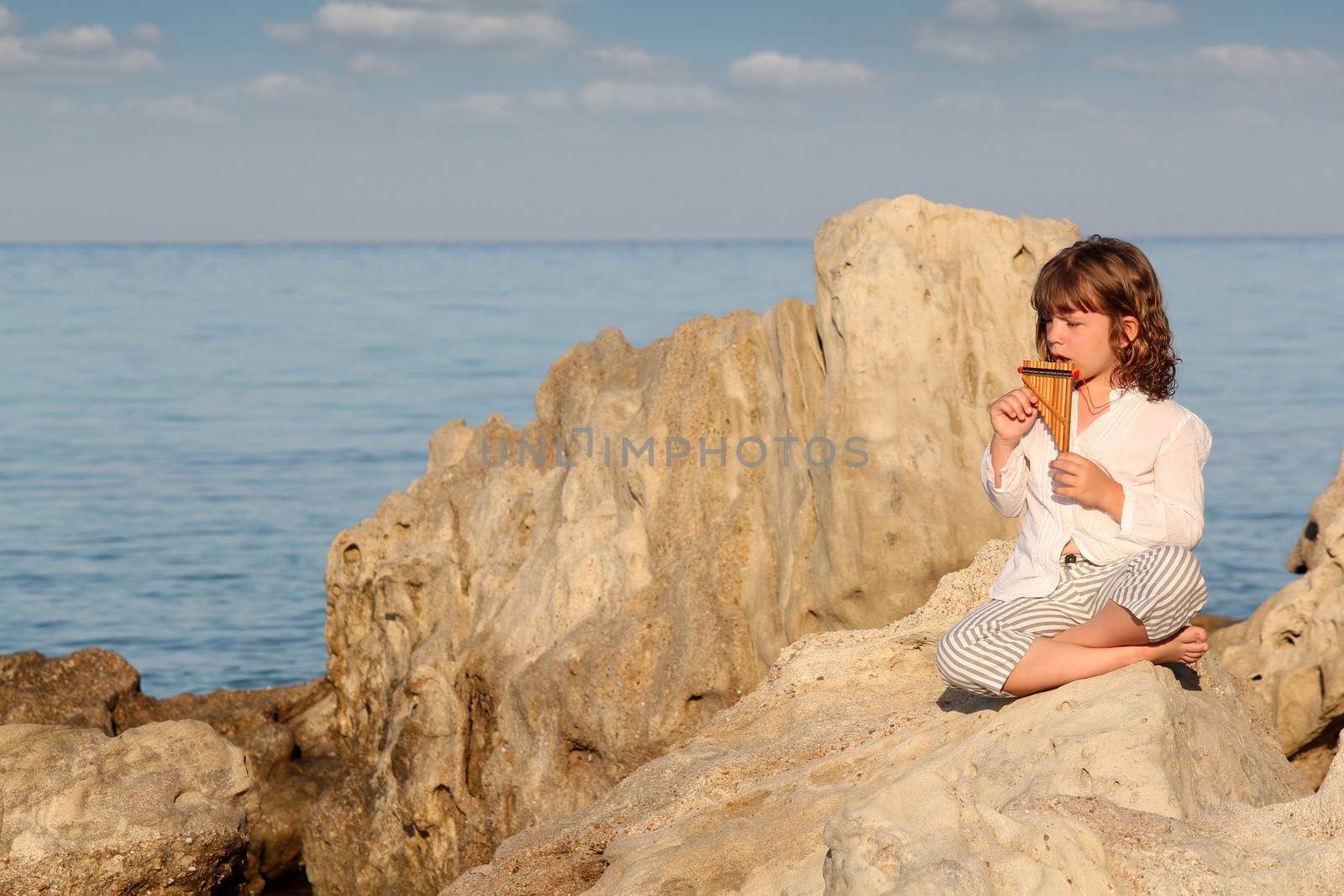 little girl playing pan pipe by the sea by goce