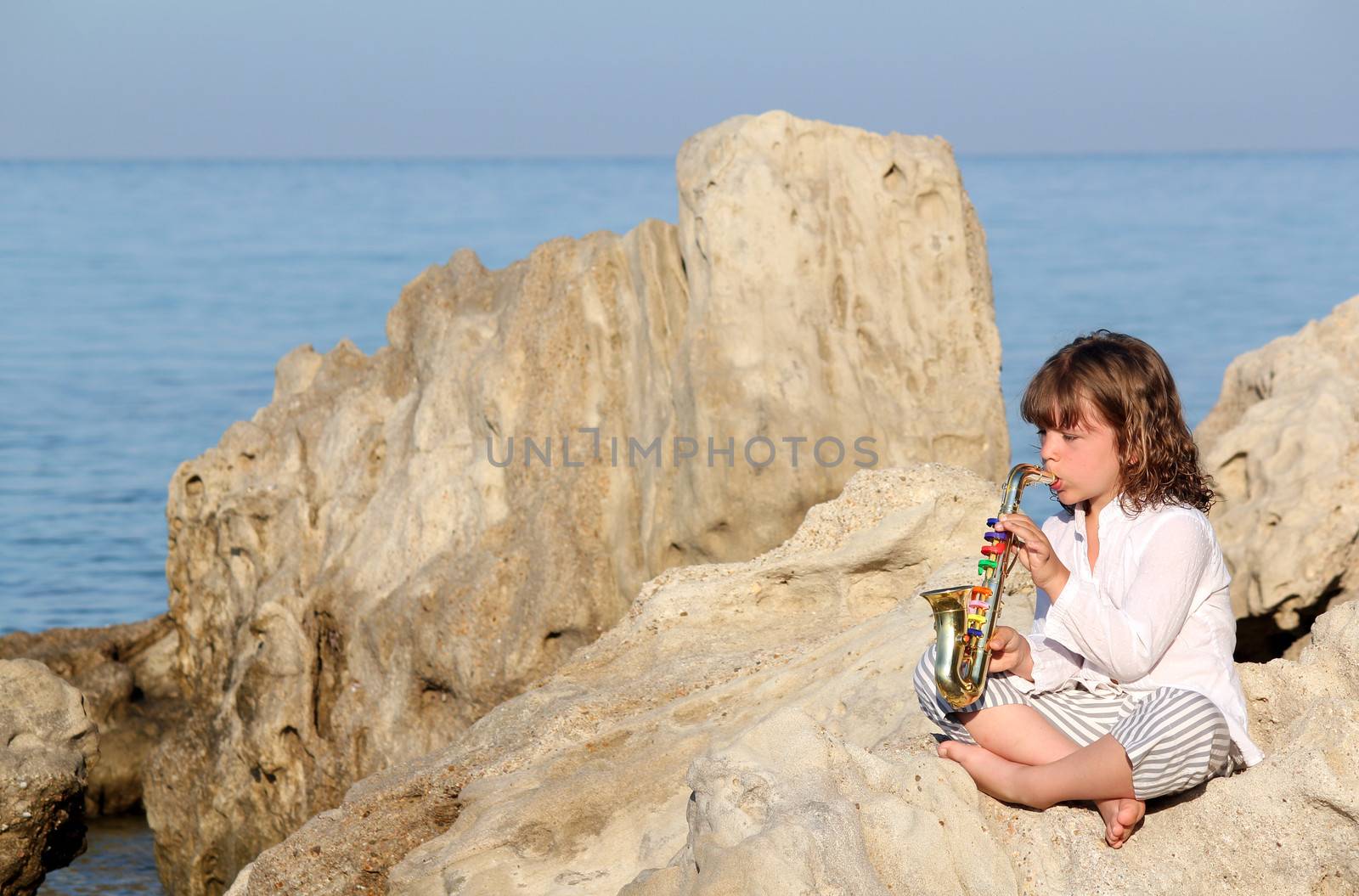 little girl playing saxophone by the sea