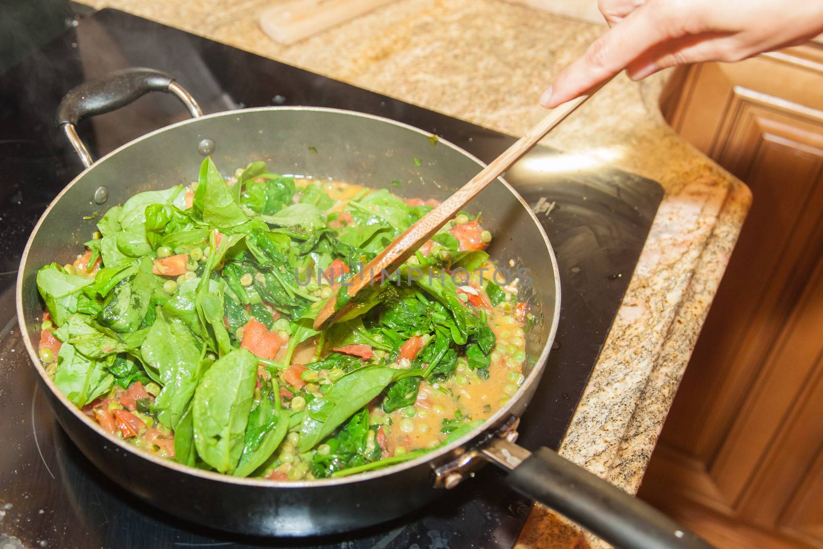 Frying spinach leaves on a large metal pan.