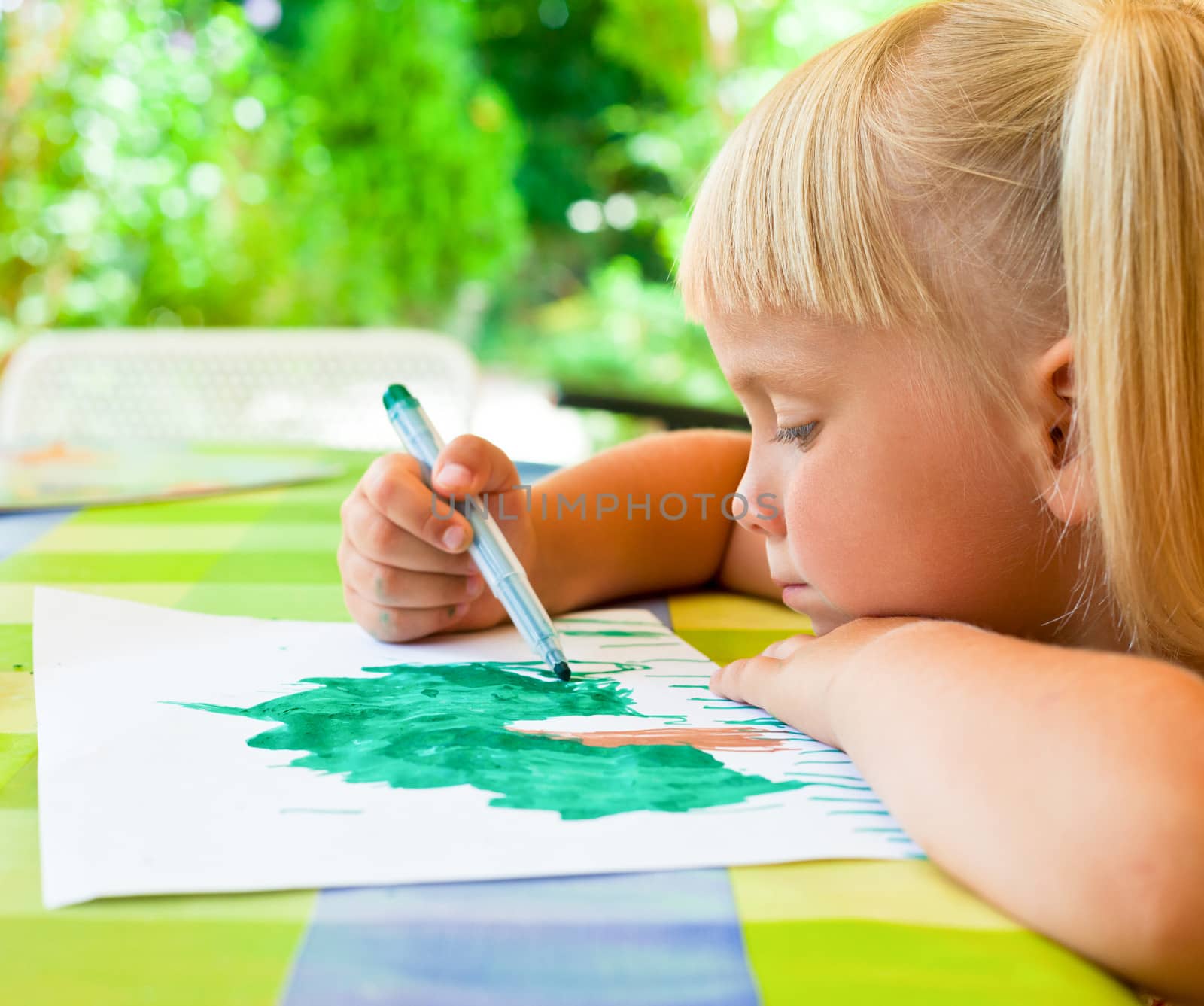 Cute 4 year old girl sitting at table drawing
