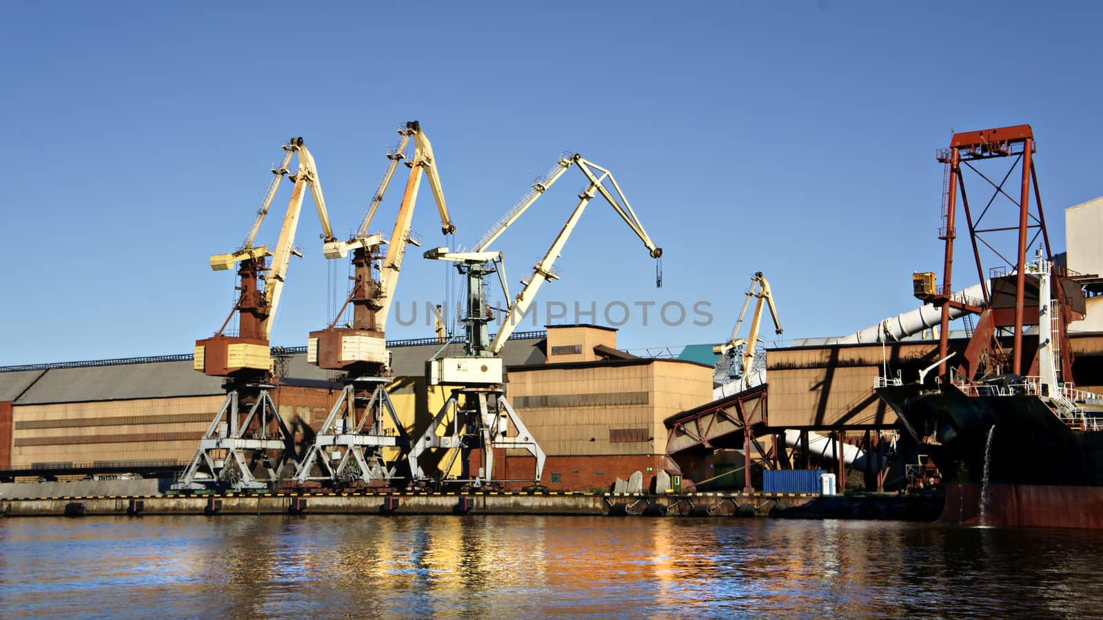 Cranes unloading a ship in a harbor                  