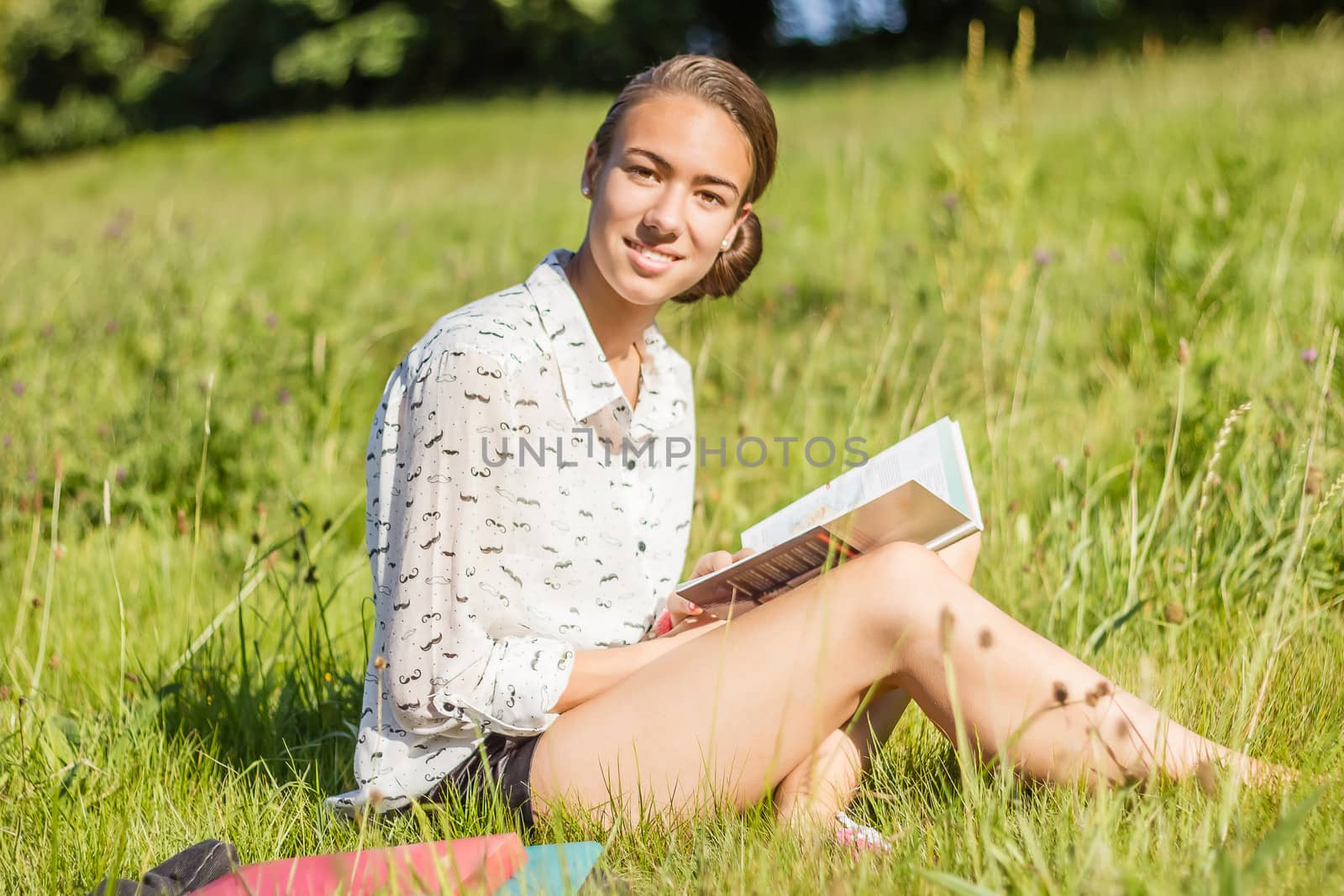 Beautiful young student reading a book in the park by doble.d