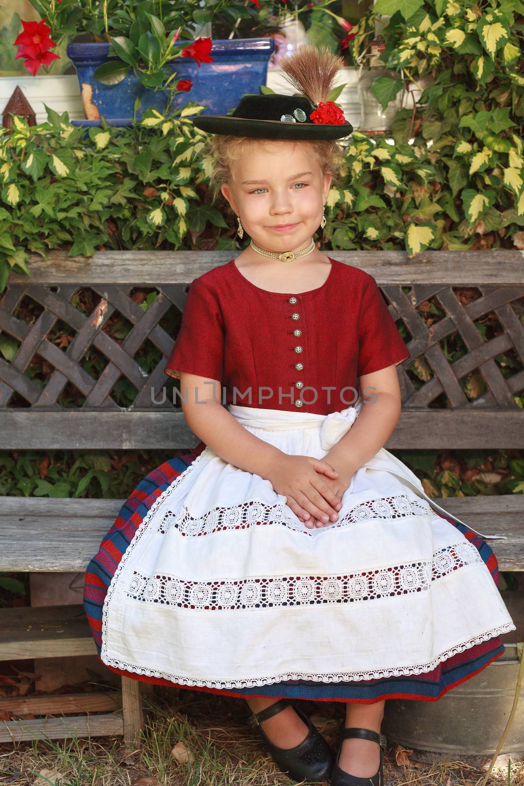 Little girl in traditional clothes sitting on a bench