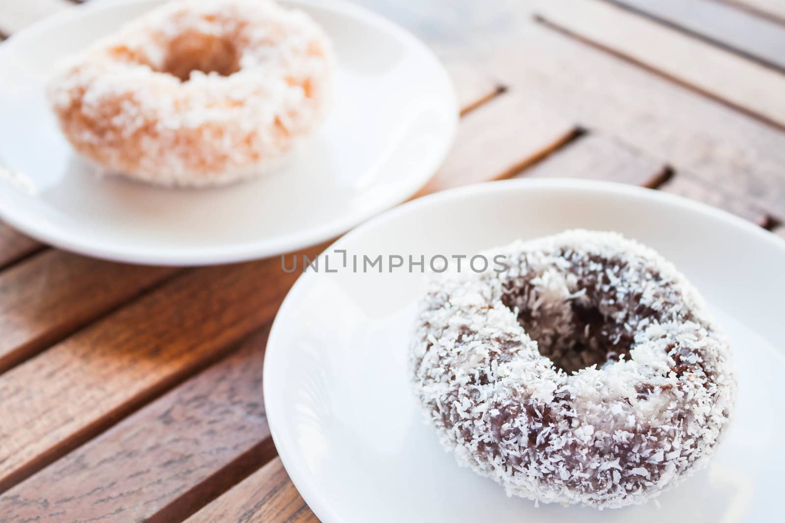 Delicious chocolate and vanilla coconut donuts on wooden table by punsayaporn