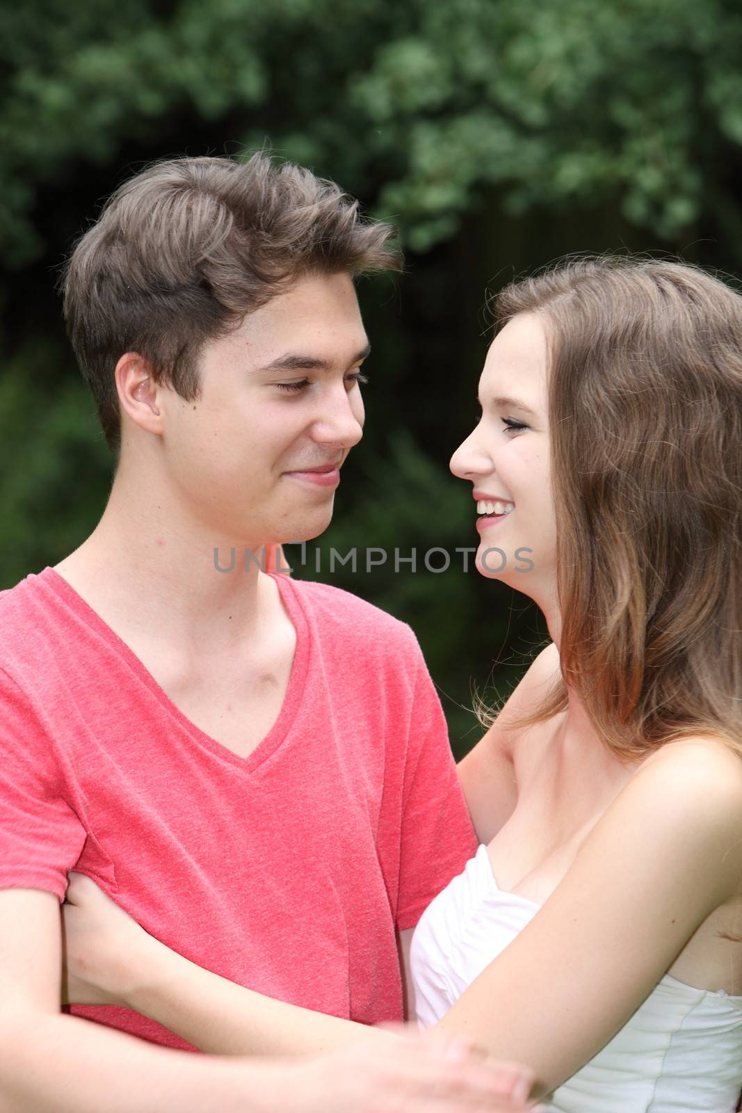 Loving young teenage couple standing holding each other and smiling while looking into each others eyes