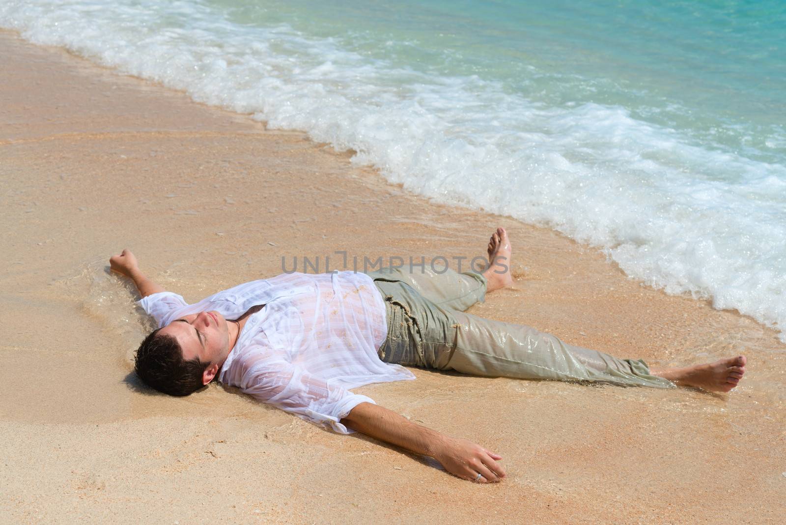 Tired man lie on sandy beach by iryna_rasko