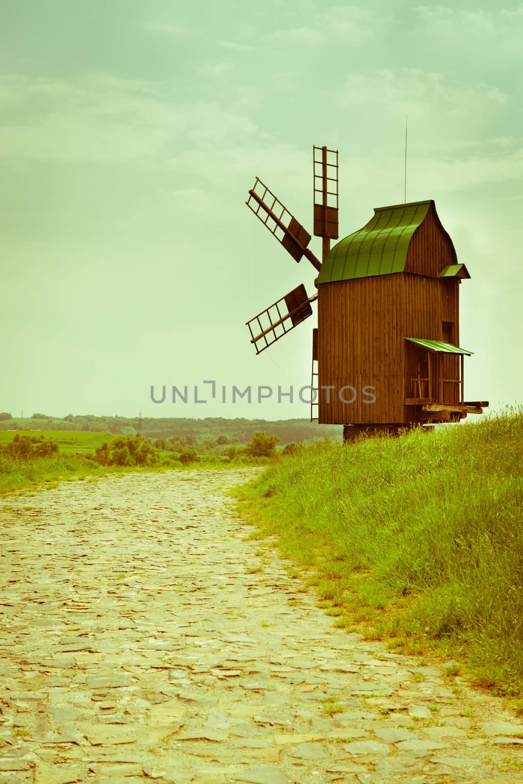 Vintage wooden windmill on stone road under blue sky
