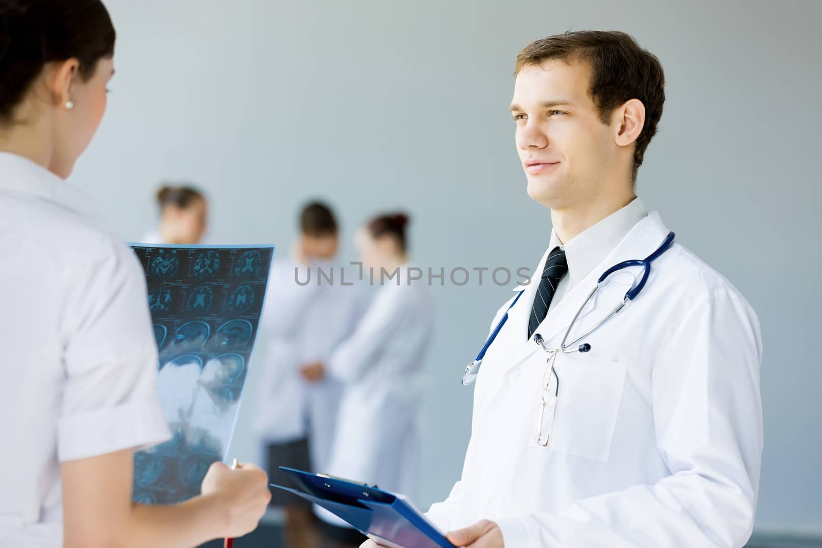 Young doctor in white uniform talking to colleague
