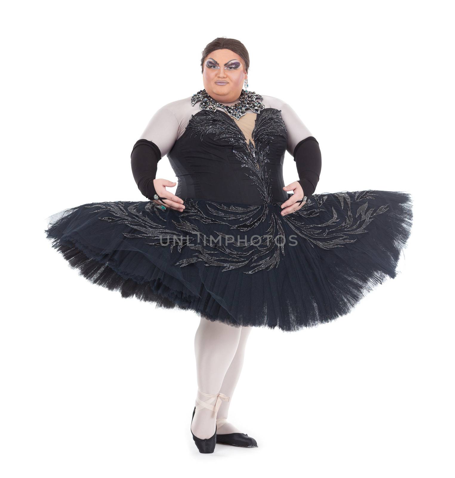 Overweight drag queen dancing in a tutu nimbly balancing on tiptoe with his foot raised in a fun caricature of a female ballet dancer, on white