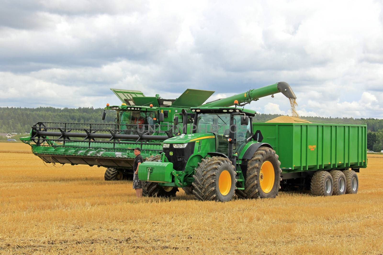 SALO, FINLAND - AUGUST 10: John Deere Combine harvester unloading grain on Palmse 1900 trailer behind Deere 7280R tractor, at the annual Puontin Peltopaivat Agricultural Show in Salo, Finland on August 10, 2013.