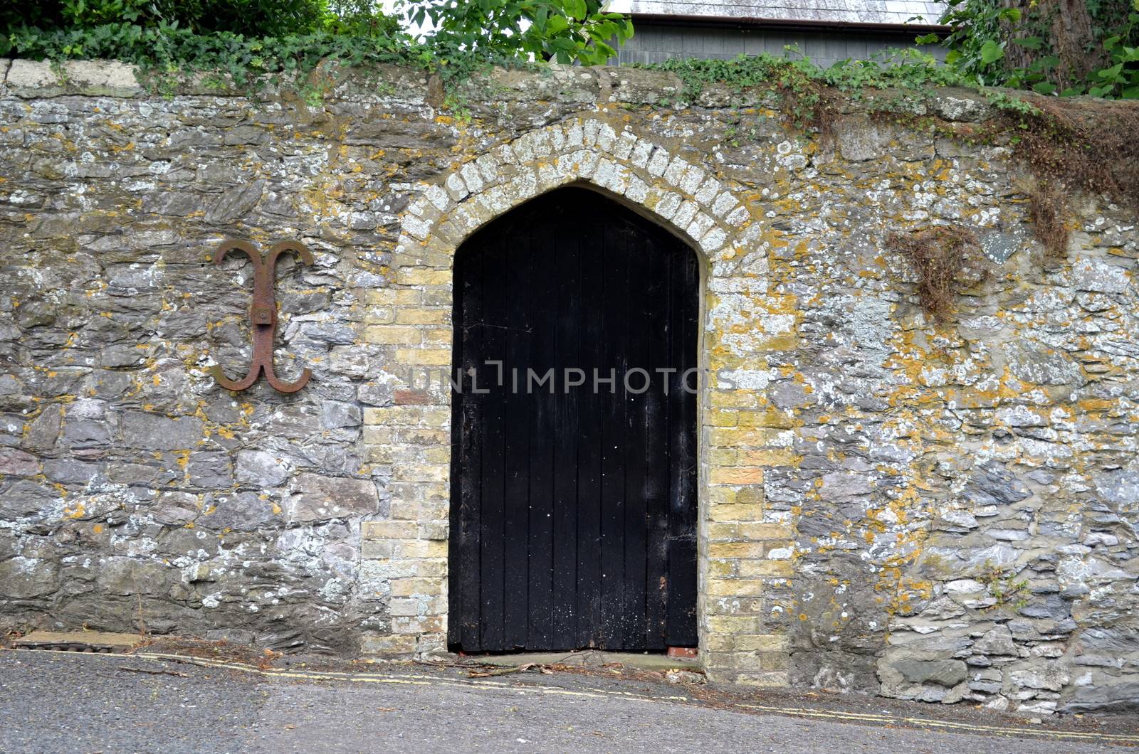 Old black wooden door surrounded by weathered stone in the historic town of Arundel, Sussex, England.