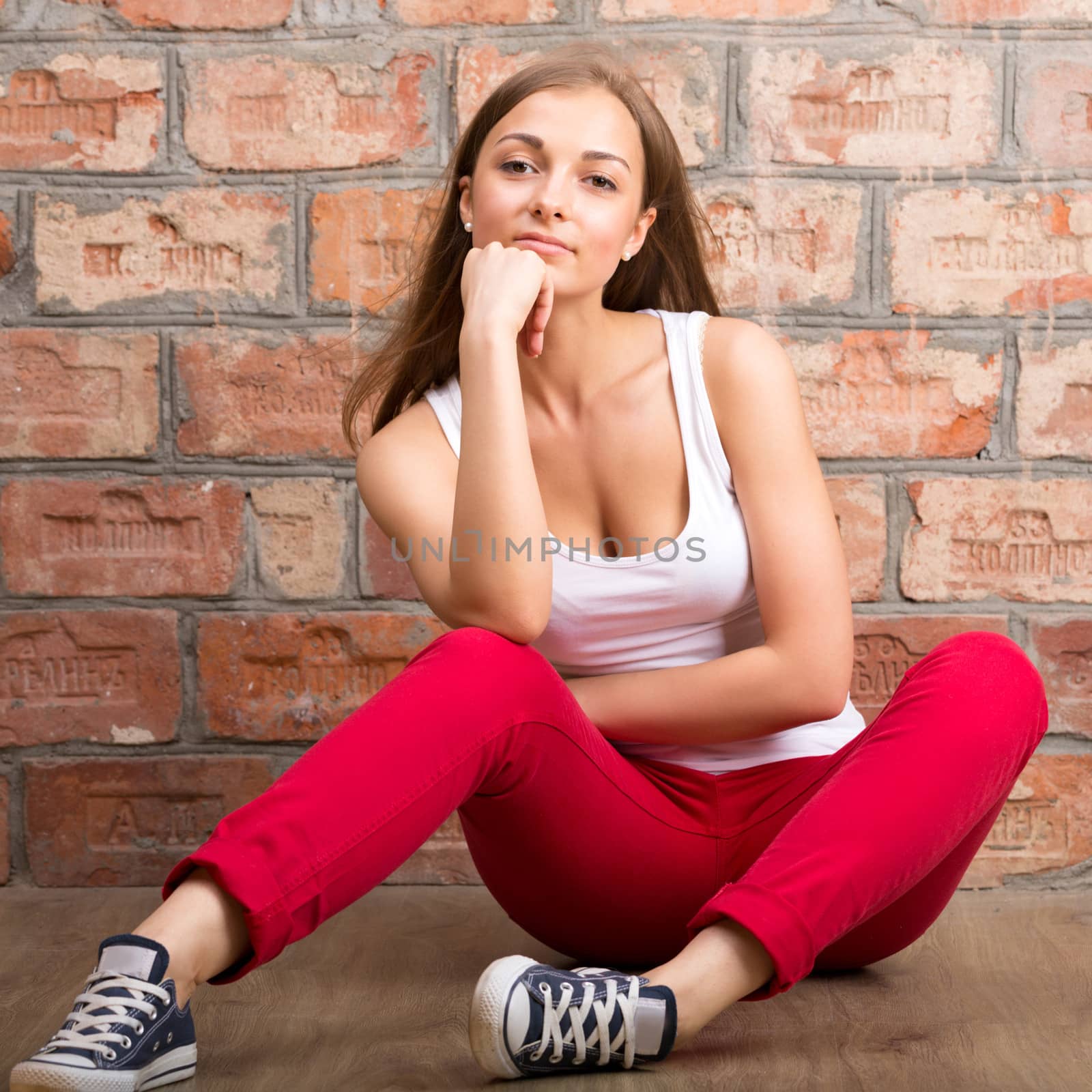 beautiful girl sitting on a brick wall background, studio portrait