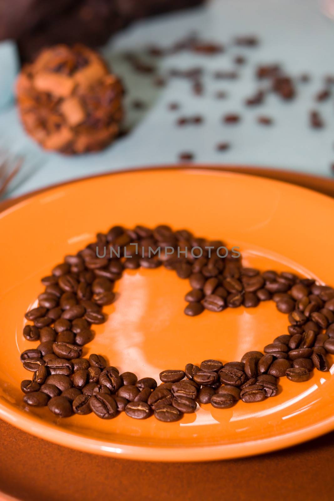 Coffee grains as a heart are laid out on a plate - Soft-focus view.
