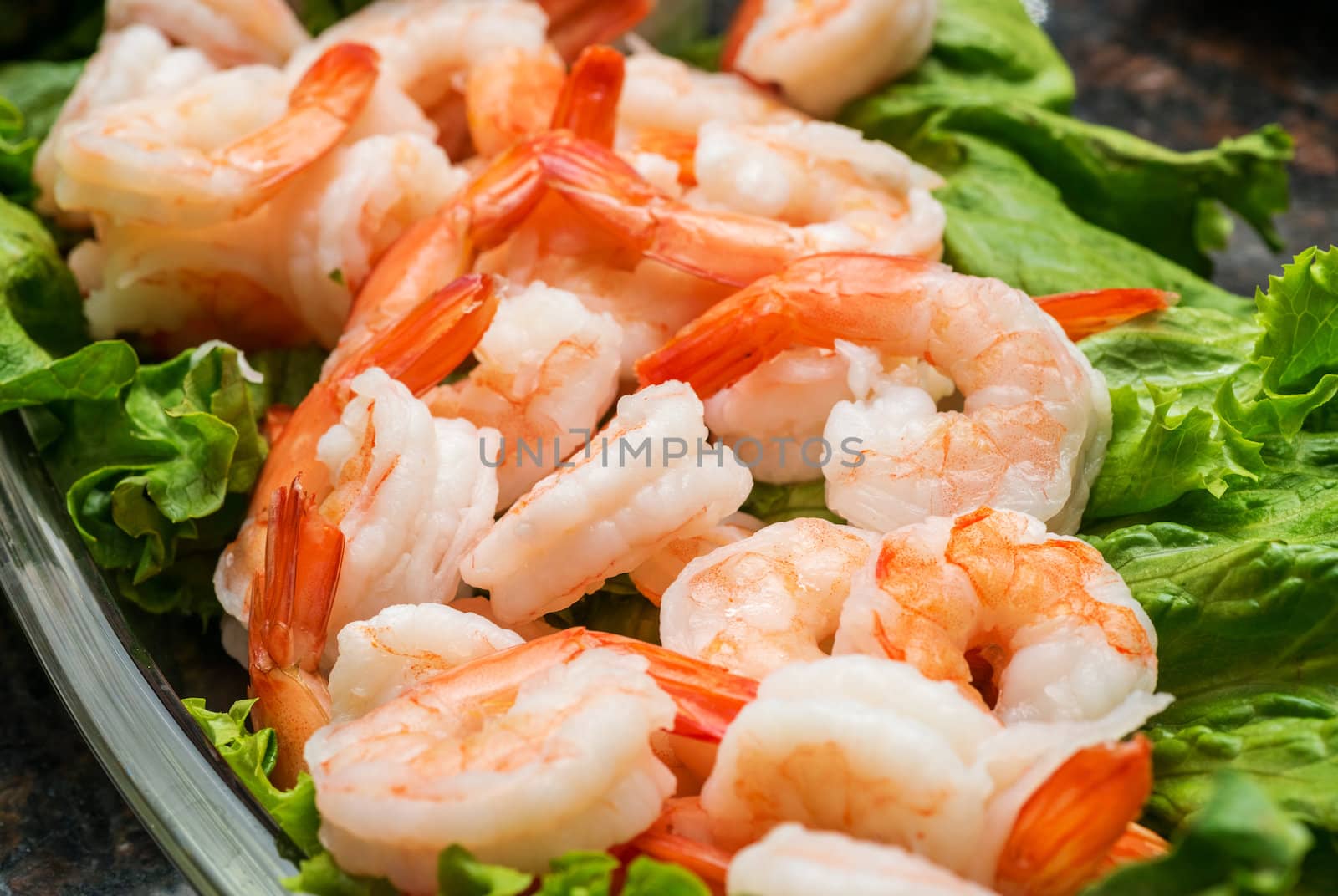A colorful dish of cooked chilled shrimp with lettuce leaves