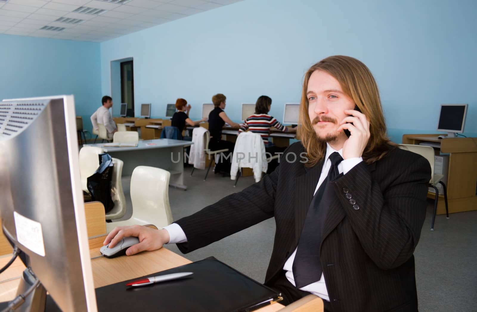 Young businessman is talking by mobile phone & receives the information by computer.