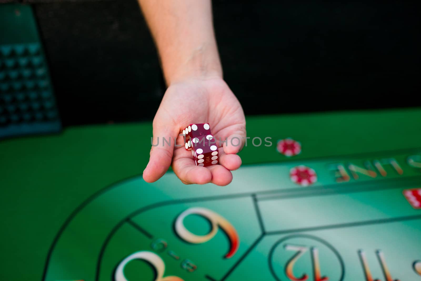 A groom holds dice above a craps table at his casino themed wedding reception.