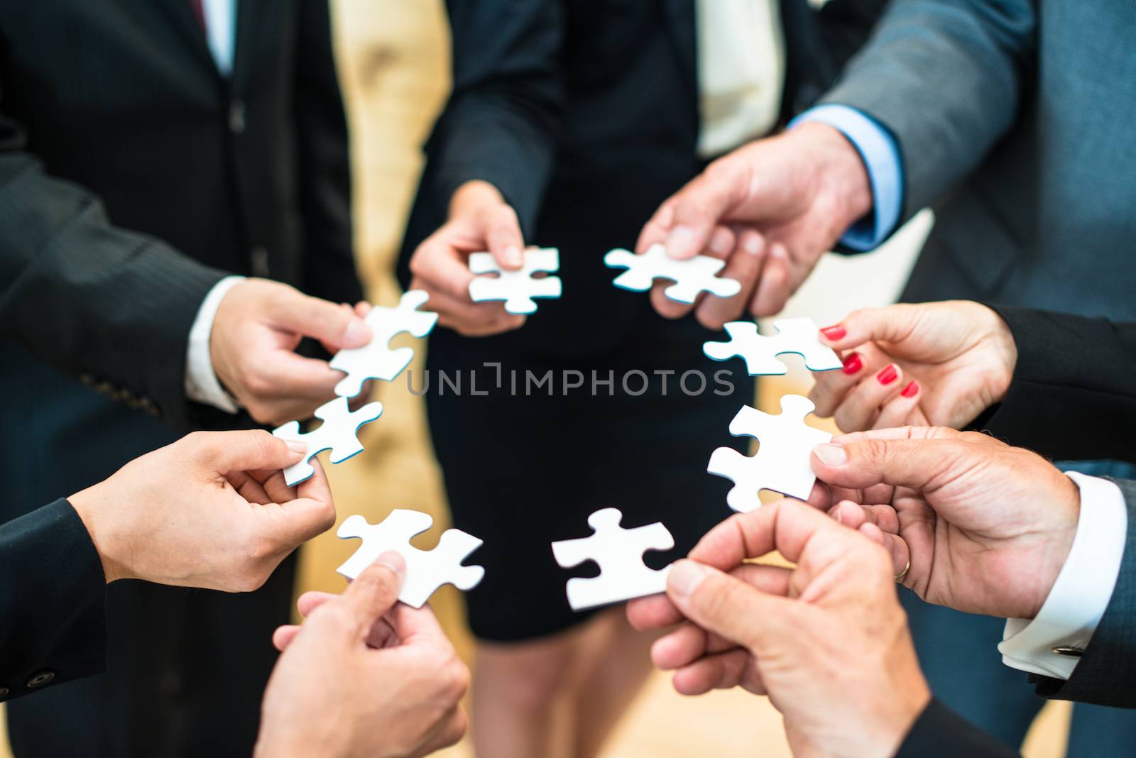 Teamwork - a group of eight business people assembling a jigsaw puzzle - representing team support and help concepts