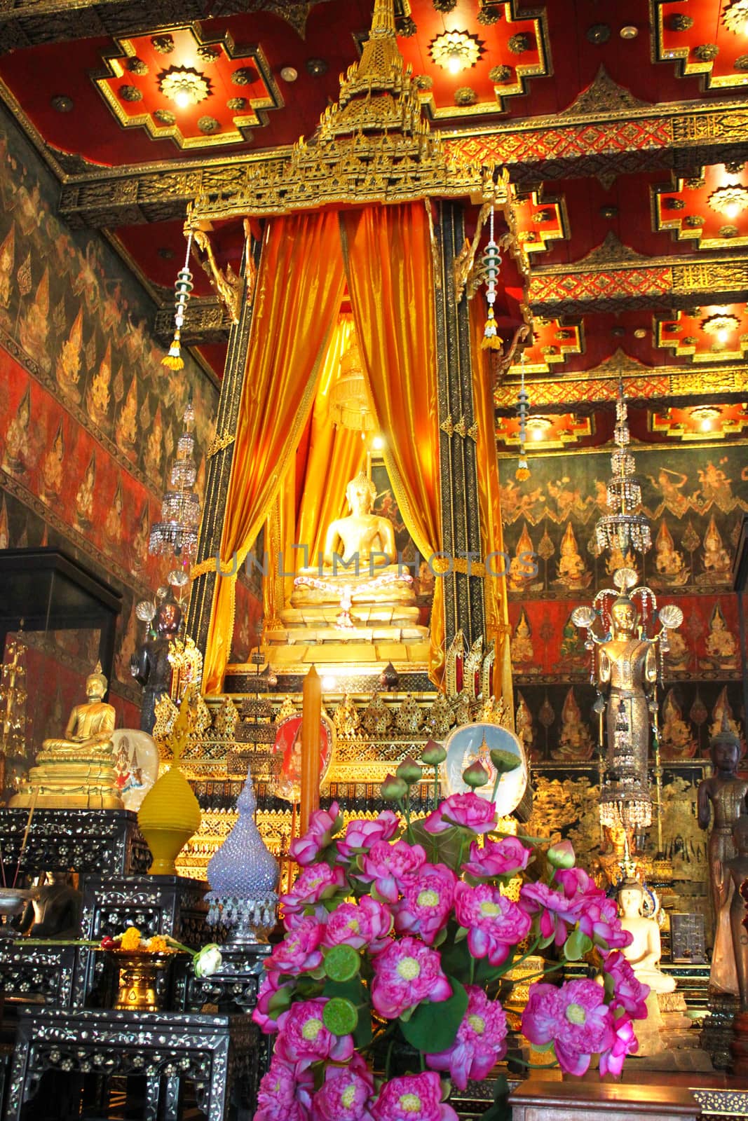 An altar with a golden buddha and lutus blossoms in a Bangkok buddist temple.